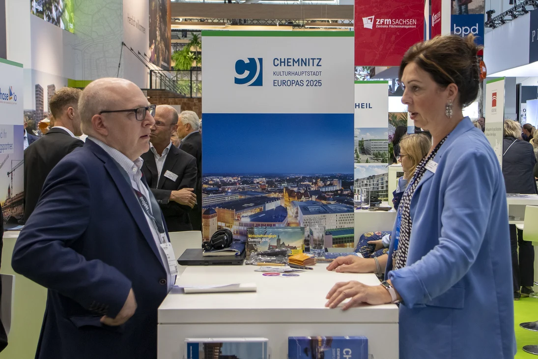 2 Personen stehen an einem Messecounter und unterhalten sich.